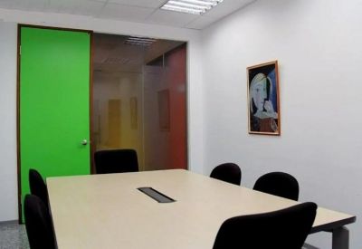Professional meeting room featuring a large light wood table, black chairs, and a green accent door.
