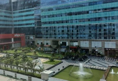 Exterior view of the glass-facade Tower B at The Corenthum featuring a manicured garden and fountain.