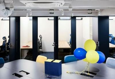 Modern meeting space featuring a large table and private soundproof phone booths in the background.