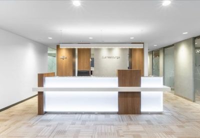 Minimalist reception area featuring a wood and backlit white front desk.