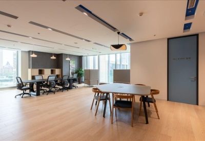 Bright, open coworking lounge with various seating arrangements and wood flooring.