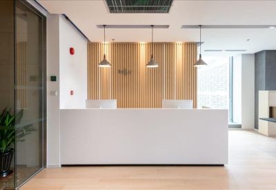 Minimalist white reception desk set against a light wood-paneled feature wall.