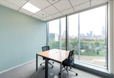 Bright corner office with two desks and a large window overlooking the city.