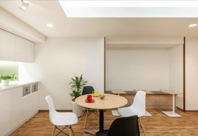 Inviting communal lounge with a round wooden table, modern white and black chairs, and a potted plant.