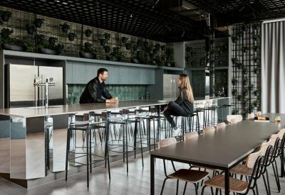 Communal kitchen and dining area with a long mirrored island and industrial ceiling.