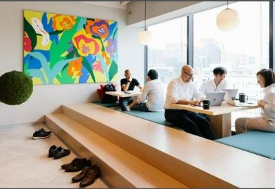 Modern coworking area with tiered wooden seating and a vibrant floral mural.