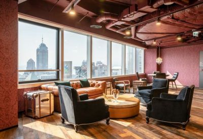 Modern lounge area with leather sofa, velvet armchairs, and a view of city skyscrapers.