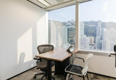 Private office suite featuring a wooden desk, two chairs, and a large window overlooking the city.