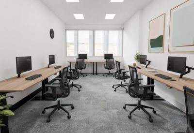 Bright open-plan office suite with long timber-look desks and ergonomic black mesh chairs.