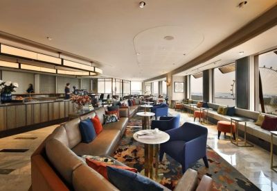 Large breakout area with plush blue armchairs, round marble tables, and a buffet counter.