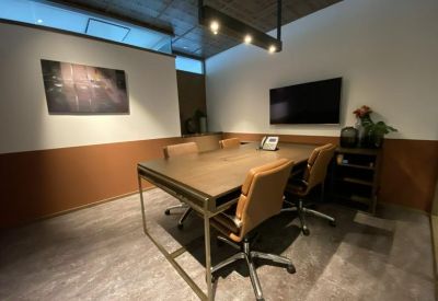 Conference room with tan leather chairs, a wooden table, and a wall-mounted TV.