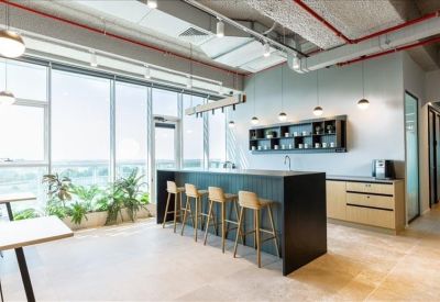 Communal kitchen area with a dark breakfast bar, wooden stools, and hanging pendant lights.