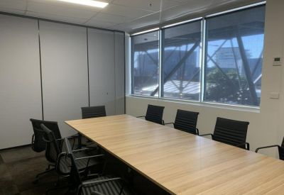 Professional meeting room with a large wooden table, black chairs, and city window views.