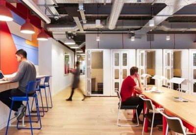 Coworking area with high-top seating, private phone booths, and people working on laptops.
