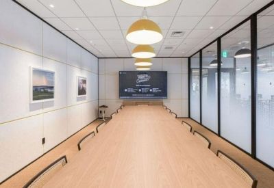 Long boardroom with a light wood table, glass walls, and minimalist globe pendant lighting.