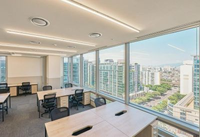 Sunlit professional office suite with several desks and panoramic city views.