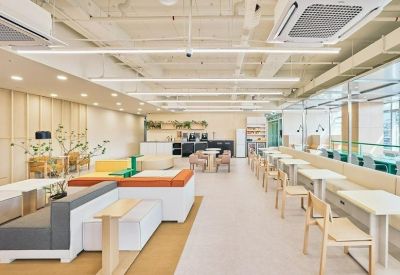 Bright open-plan coworking area with various seating options and colorful sofas.