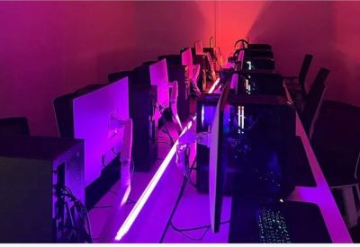 Esports or gaming setup with multiple monitors and vibrant purple and red LED lighting.