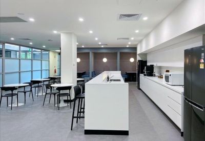 Modern communal kitchen and breakout area with white counters and a dining space.