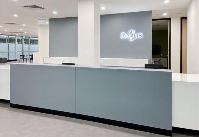 Bright reception area featuring a grey front desk and clean white walls.