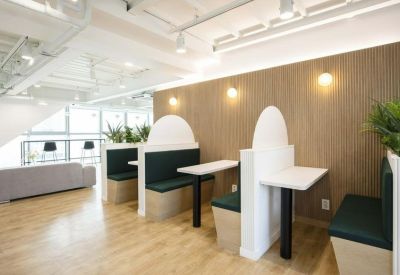 Private seating booths with dark green cushions against a wood-slat feature wall.