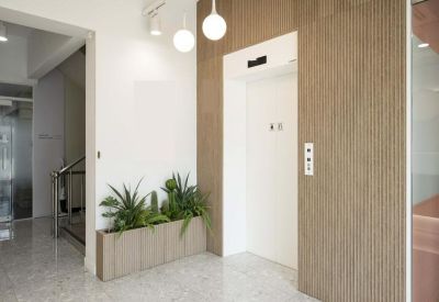 Minimalist elevator lobby featuring wood-paneled walls and indoor greenery.