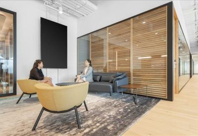 Casual meeting corner featuring yellow armchairs, a grey sofa, and wooden slatted wall dividers.