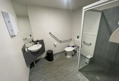 Spacious accessible bathroom and shower facility with modern grey tiling and grab rails.