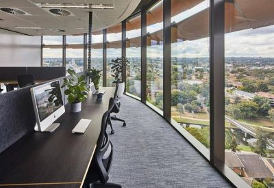 Modern office workspace with sleek desks and floor-to-ceiling windows offering expansive city views.
