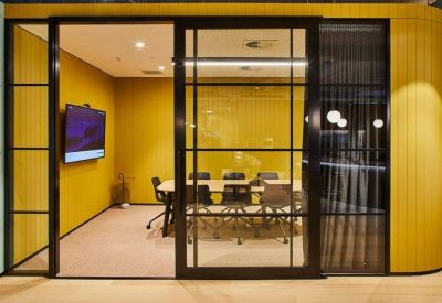 Modern glass-walled meeting room with yellow feature walls and a large conference table.