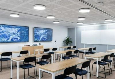 Modern training room featuring tiered desks and dual presentation screens.