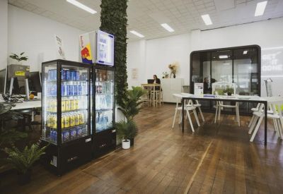 Breakout area with a glass beverage fridge, indoor plants, and a private phone booth.
