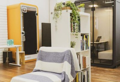 Quiet zone featuring a striped lounge chair, bookshelf, and soundproof work pods.
