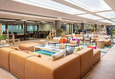 Large open-plan coworking space with tan leather sectional sofas and skylights.