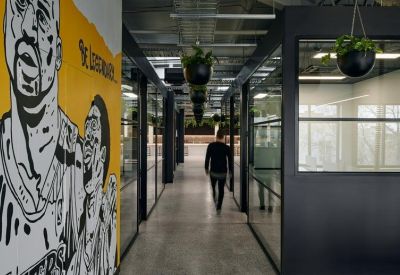 Industrial corridor featuring a large wall mural and glass-walled offices.