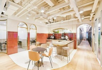 Modern lounge area with round tables, curved red tile walls, and exposed ceiling pipes.