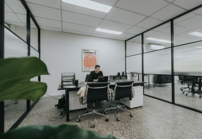Private office with black mesh chairs, white desks, and glass partitions.