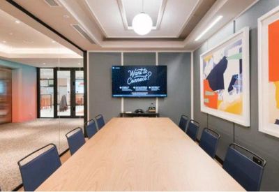Professional meeting room with a large wooden table and vibrant abstract wall art.