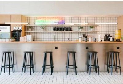 Modern office kitchen and bar area with high stools and a tiled backsplash.
