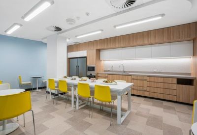 Communal kitchen and dining area with a long white table and bright yellow chairs.
