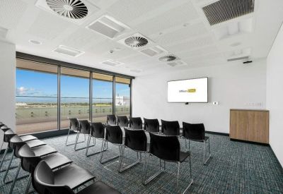 Classroom-style meeting room with rows of black chairs facing a presentation screen.