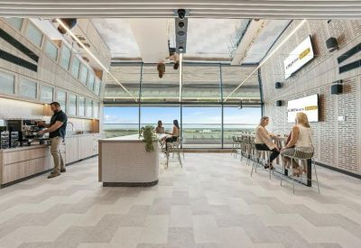 Spacious breakout lounge with a coffee station, chevron flooring, and floor-to-ceiling windows.