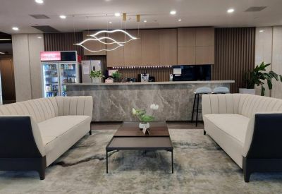 Modern communal cafe area with a marble-finish bar, designer light fixture, and plush cream sofas.