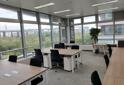 Spacious open-plan workspace with wooden desks, ergonomic chairs, and large windows overlooking the city.