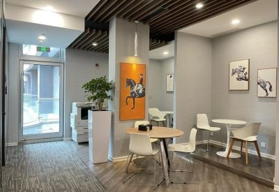 Small breakout area with cafe tables, white chairs, and vibrant equestrian wall art.