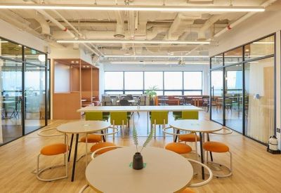 Wide view of a collaborative lounge area with glass-walled meeting rooms.