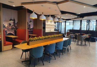 Spacious communal lounge with booths, blue chairs, and a long dining table.
