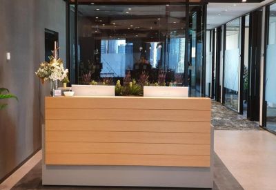 Modern wooden reception desk with glass partitions and view of the corridor.