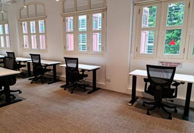 Open-plan workspace featuring several individual desks with ergonomic chairs by windows.