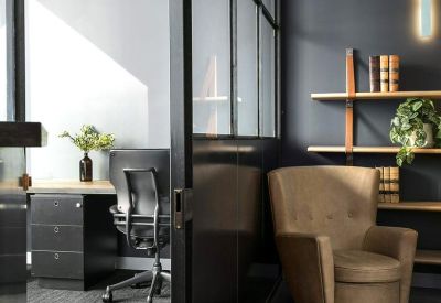 Private office suite featuring a leather armchair, bookshelves, and glass partitioning.